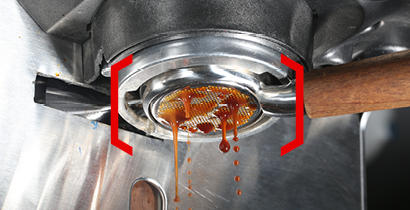 Image of coffee an espresso machine's portafilter, with coffee slowly dripping from the filter into a cup below, framed by red brackets