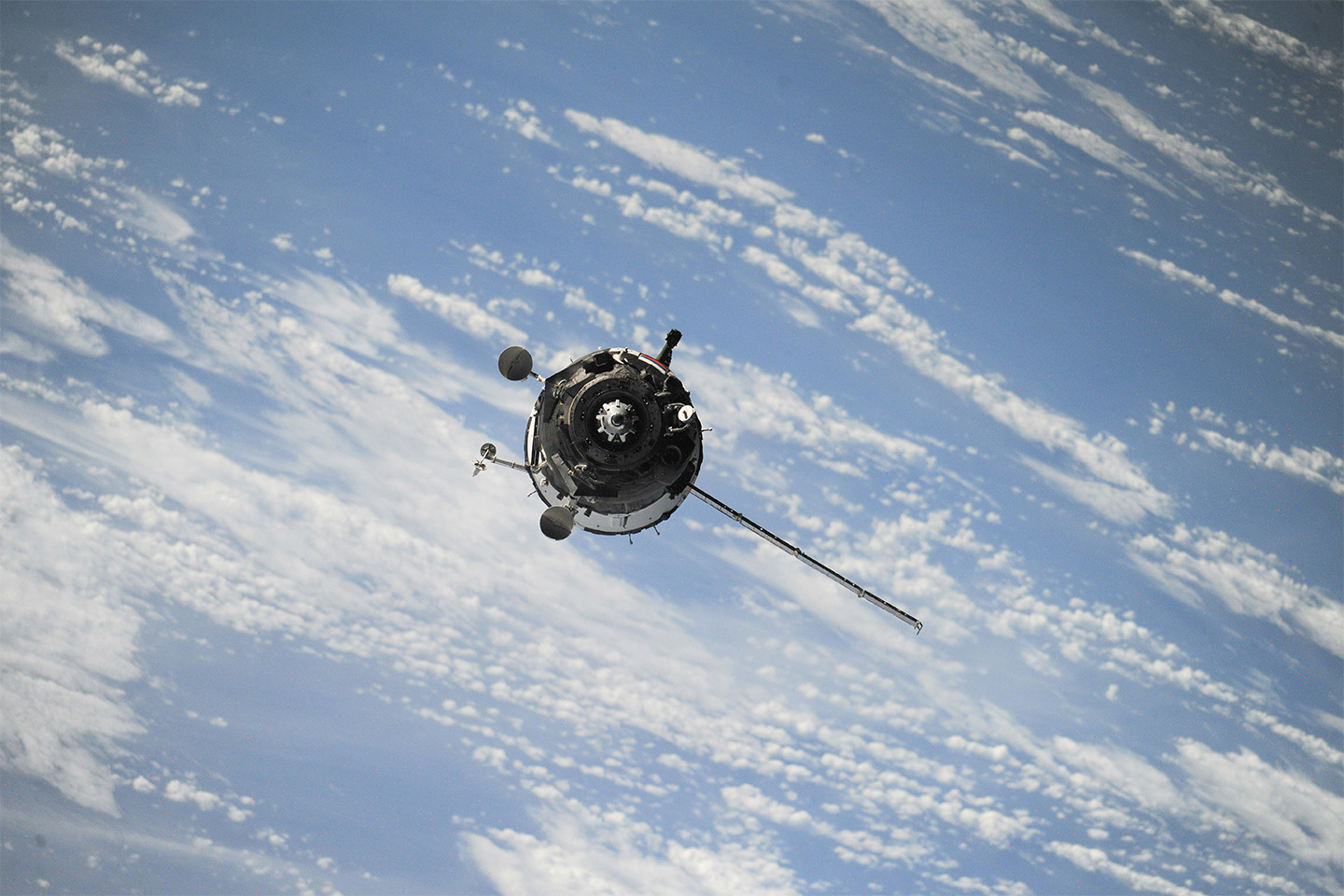 Satellite floating with a blue cloudy sky behind it 