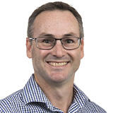 Peter Chapman smiling at camera wearing a blue shirt and glasses
