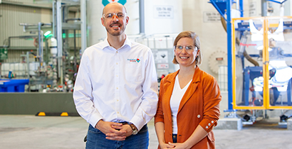 Two people standing in a factory or industrial plant